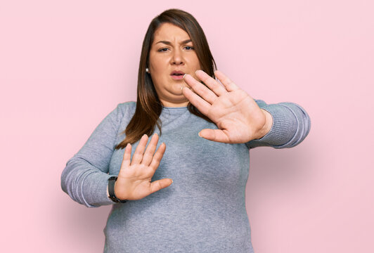 Beautiful brunette plus size woman wearing casual clothes doing stop gesture with hands palms, angry and frustration expression