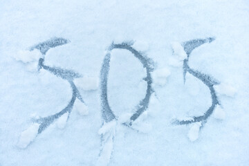 SOS is written on white snow. The concept of emergency situations due to winter disasters, landslides, blockages, avalanches.