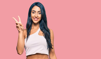 Obraz premium Beautiful hispanic woman wearing casual clothes smiling looking to the camera showing fingers doing victory sign. number two.