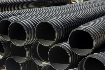PVC tubes plastic pipes stacked in rows at construction site on reconstruction of the city drain...