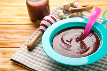 Bowl of healthy baby food on wooden table, closeup. Space for text