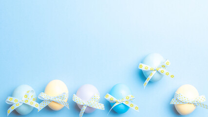 Easter background. Colorful egg with tape ribbon on pastel blue background in Happy Easter decoration. Spring holiday top view concept.