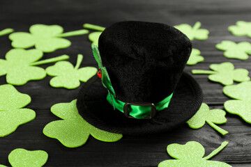 Leprechaun's hat and decorative clover leaves on black wooden background. St. Patrick's day...
