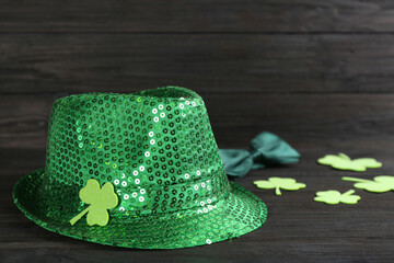 Leprechaun's hat and decorative clover leaves on black wooden background. St. Patrick's day...