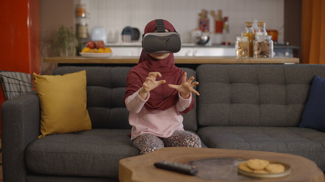Little girl in a turban wearing virtual reality glasses (vr glasses). Augmented reality. Happy cute little girl playing games using 3D vr glasses.  - Powered by Adobe