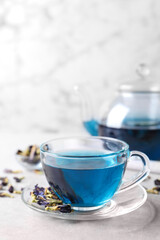 Glass cup of organic blue Anchan on light table, space for text. Herbal tea