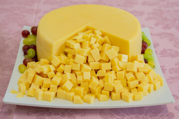 Cheese with many small pieces and grapes around it.