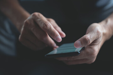 Close up, man hand using mobile phone chatting via social media apps with screen light