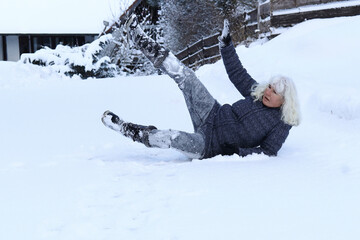 Eine Frau ist auf einem schneebedeckten Straße ausgerutscht und hingefallen