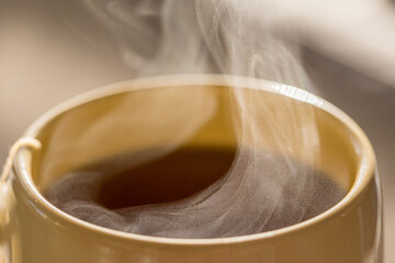 Steaming hot drink in ceramic cup close up view