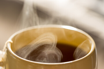 Steaming hot drink in ceramic cup close up view