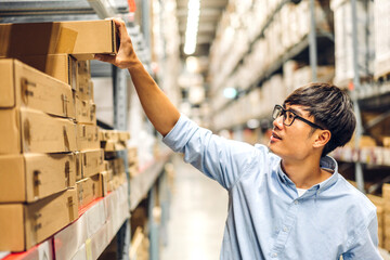 Portrait of smiling asian engineer man order details checking goods and supplies on shelves with goods background in warehouse.logistic and business export