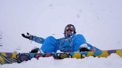 Cheerful beautiful young girl snowboarder throws snow flakes. Winter fun at the ski resort.