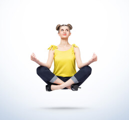 Happy young women in casual clothes meditating levitating in the air on light blue background....