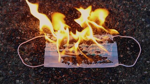 A medical face mask burns in flames as the coronavirus pandemic ends. The fire represents a protest of the mask mandate imposed by government officials during the Covid-19 virus outbreak. 