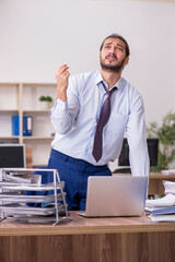 Young businessman employee unhappy with excessive work in the of