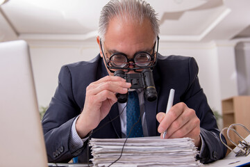 Old male employee auditor wearing many glasses at workplace