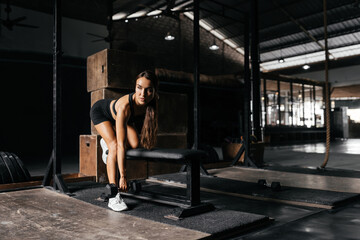 Naklejka na ściany i meble Fit young woman at a crossfit style on dark gray background. Fitness, functional, training, and lifestyle concept