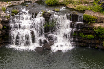 Cascading waterfall. A waterfall is an area where water flows over a vertical drop or a series of steep drops in the course of a stream or river. Waterfalls also occur where meltwater drops over the e