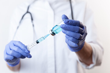 Doctor in gloves filling up syringe from bottle with vaccine, medicine