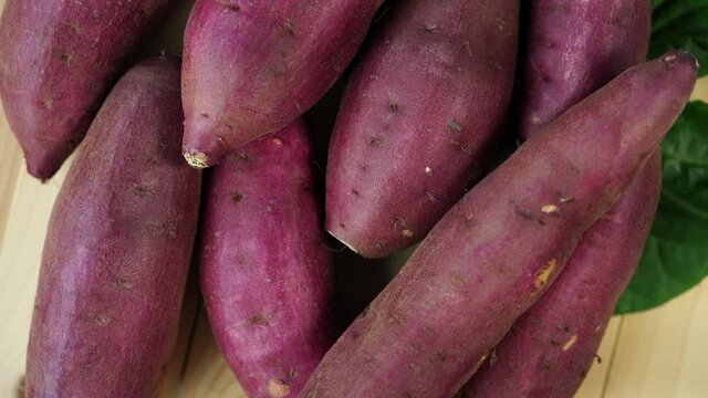Top view Rotate Fresh sweet potato closeup, Japanese Sweet Potato on wooden table in garden.