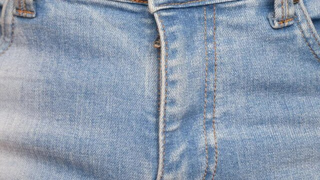 Close-up of man's hands fastening a clasp on his jeans and the button