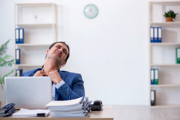 Naklejka premium Young male employee unhappy with excessive work in the office