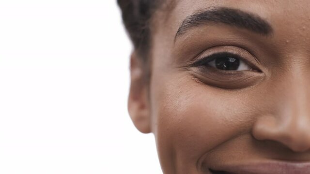 Half face portrait of pretty african american lady smiling to camera, white studio background, free space