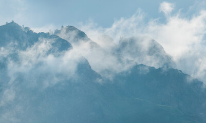 Naklejka na ściany i meble Mountain peaks in the clouds. Fog and blue haze.