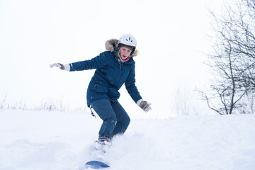 Fototapeta na wymiar Girl rides a snowboard from the mountain
