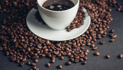 coffee beans and a cup on a white saucer dark background drink