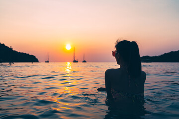 Fototapeta premium Silhouette of Travel asian woman relax on sea beach in sunset at Thailand