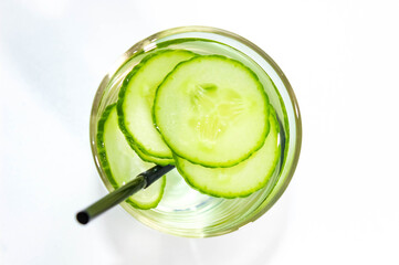 Detox water with a sliced cucumber in a glass with a straw for drinking. The concept of losing weight and cleansing the body. vertical frame.