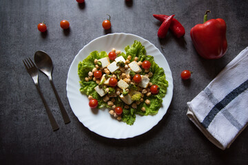Chicken chick peas and cherry tomato salad on a white plate with use of selective focus  with fork and spoon