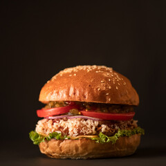 Classic American burger with grilled meat on black background. Fast food menu concept. Nutritious snack or lunch. food. Square format for posting on social media.