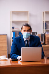 Young male employee working in the office wearing mask