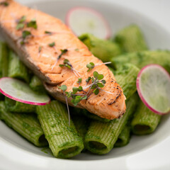 Food plate with Fried salmon fish. Microgreens, pasta and thin slices of fresh radish on it. Simple and healthy wholesome food. Close up shot. Soft focus. Square format for posting on social media.
