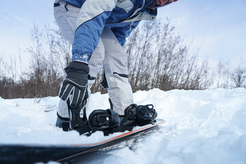 The guy fastens the binding on the snowboard