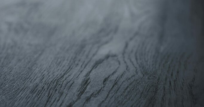 Slow motion handheld shot of black painted oak surface
