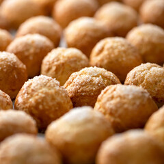 Hot crispy buns just out of the oven. Rows of white round crispbreads or donuts are cooling. Baking cream puffs or eclairs background.