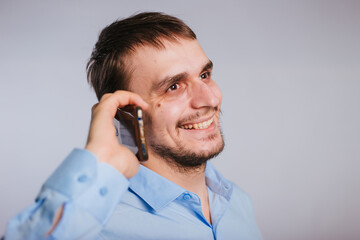 A man in a blue shirt on a white background talking on the phone.