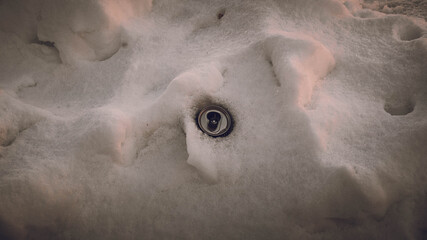 The aluminum empty jar is hidden in the snow. Environment.