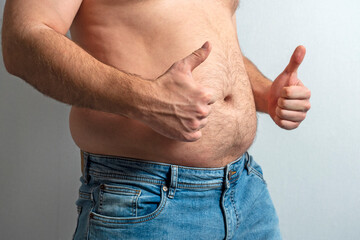a fat man in jeans with a bare stomach and a finger raised in the air. The concept of body...