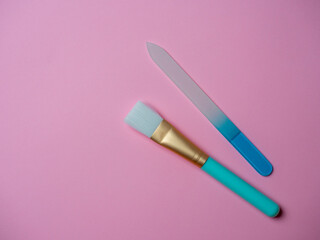 nail file and a paint brush for applying face masks on a pink background. Cosmetic accessories