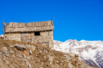 Fototapeta premium Winter evening landscape in french Alps. Old stone abandoned house on the mountain.