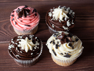 Top view of delicious sweet chocolate cupcakes lying on a wooden background. The sweetness is decorated with pieces of chocolate