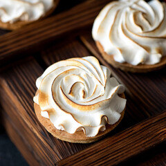 Cakes with airy cream on wooden tray. Circle sweet gift or present for beloved person. Holiday or festive food concept. Exquisite goodies for refined taste. 1x1 format.