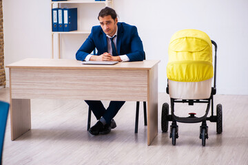 Young male employee looking after kid at workplace