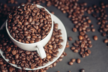 a cup with coffee beans stands on a saucer on a gray background close-up