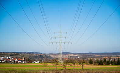 A closeup shot of a transmission tower in the field under a blue sky